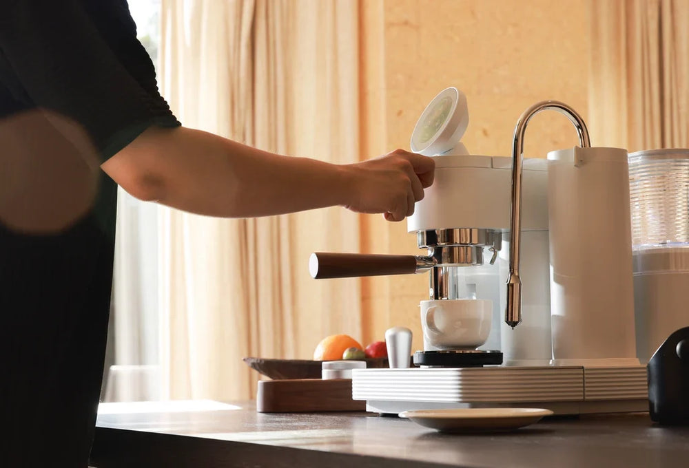 1. Operating a white Meraki espresso machine with a cup positioned beneath the portafilter