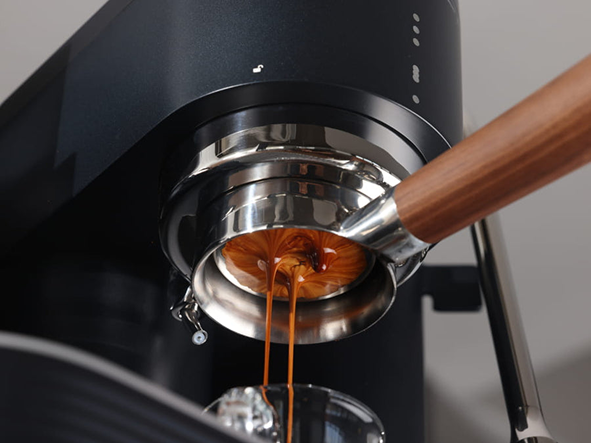 Espresso flowing from a portafilter on a black Meraki espresso machine